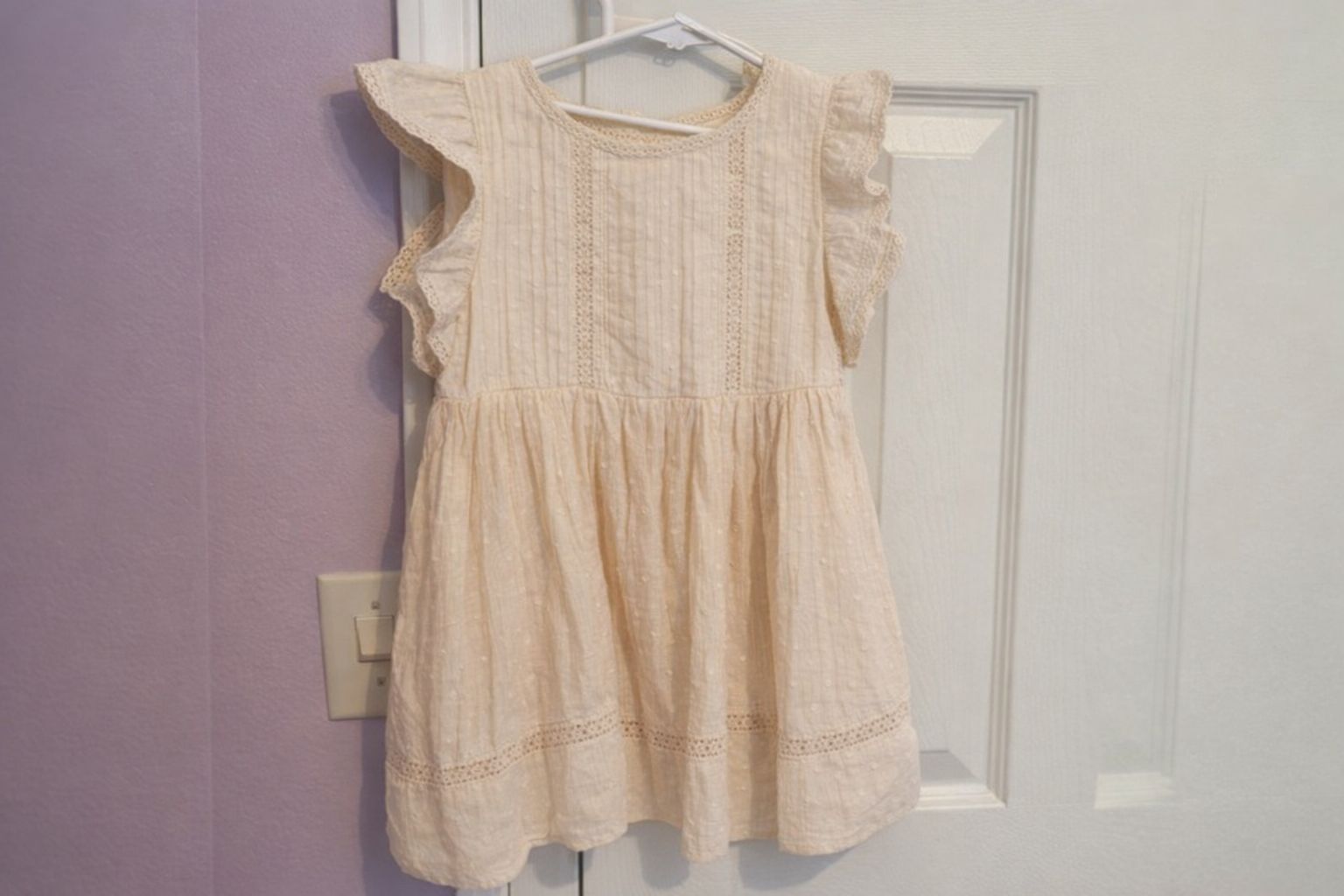Robe pour enfant de couleur crème avec volants et broderie anglaise.